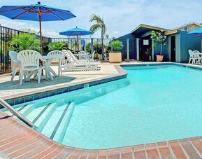Outdoor pool with lounge chairs at Travelodge LAX By Wyndham.