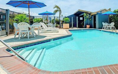 Outdoor pool with lounge chairs at Travelodge LAX By Wyndham.