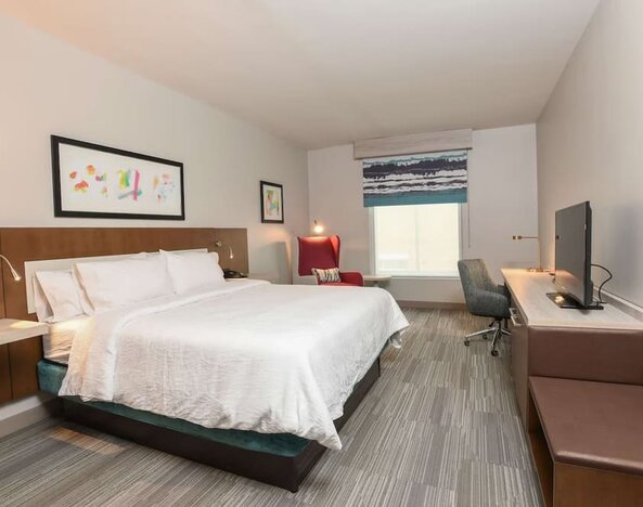 Bright and spacious day use room with king bed, work desk and TV screen at Hilton Garden Inn Cincinnati Midtown.