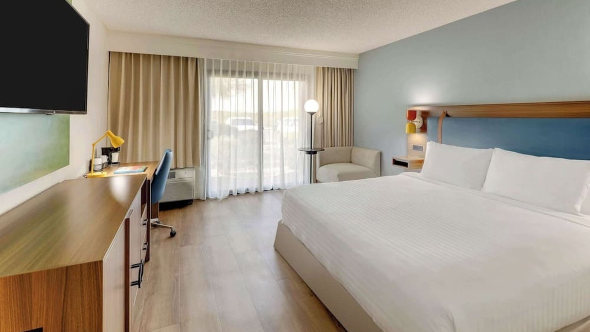 Day use room with king bed, work desk, sofa, TV screen and floor to ceiling window at Sonesta Select Scottsdale At Mayo Clinic Campus.