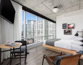 Delux king room with work desk and a view of the city at Moxy Boston Downtown.