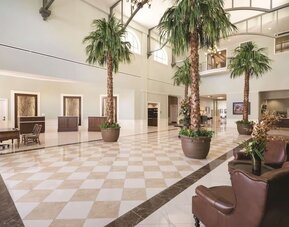 Hotel reception with lounge seating and workspace at Embassy Suites By Hilton Savannah.
