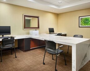 Business center with computers, printer and comfortable seating at Embassy Suites By Hilton West Palm Beach Central.