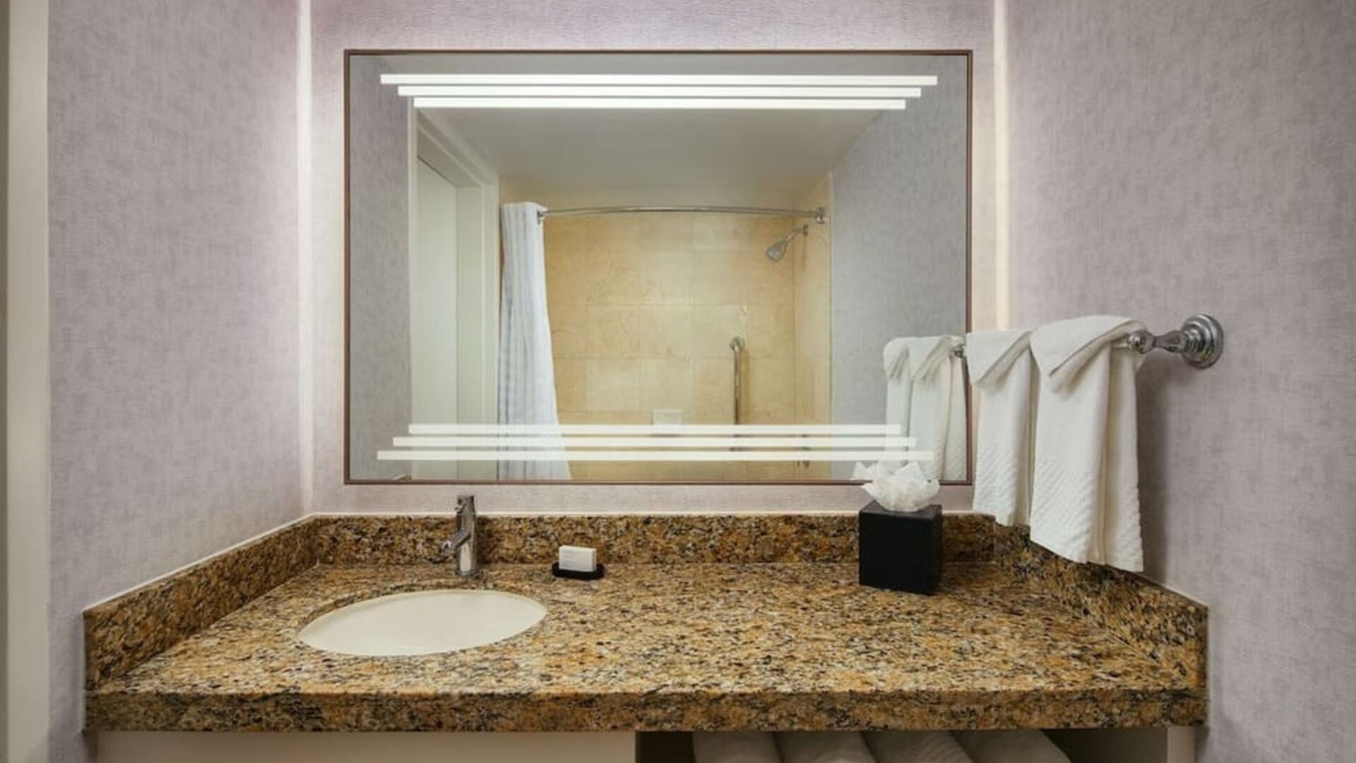 Private guest bathroom with shower and free toiletries at Embassy Suites By Hilton West Palm Beach Central.