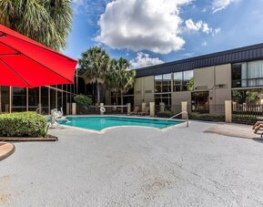Hotel patio with lounge chairs and outdoor pool at Red Roof PLUS+ & Suites Houston - IAH Airport SW.