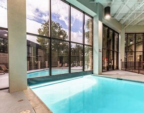 Combined indoor-outdoor pool with lounge seating at Red Roof PLUS+ & Suites Houston - IAH Airport SW.