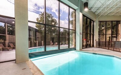 Combined indoor-outdoor pool with lounge seating at Red Roof PLUS+ & Suites Houston - IAH Airport SW.