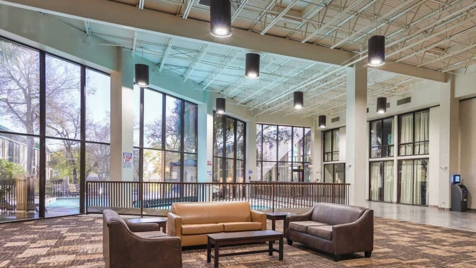 Comfortable lobby and coworking space with lots of natural light at Red Roof PLUS+ & Suites Houston - IAH Airport SW.