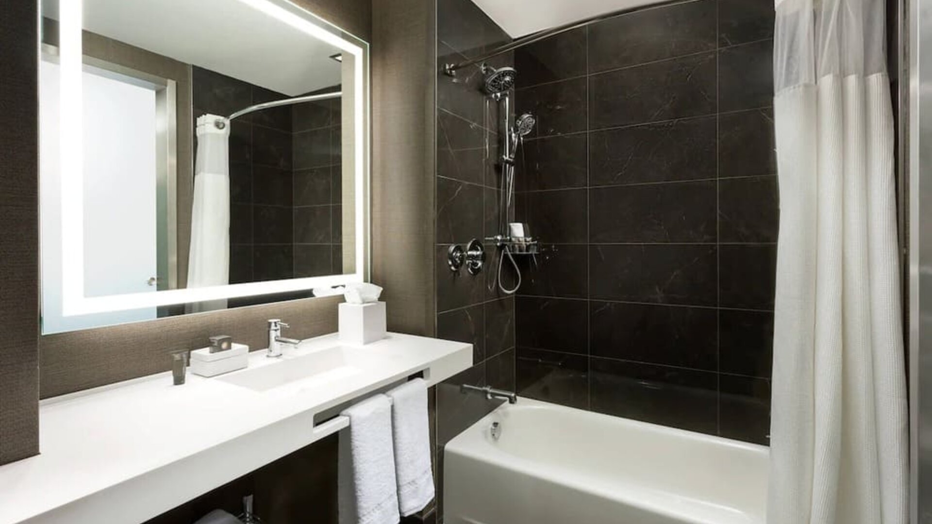 Private guest bathroom with combined shower and tub at AC Hotel New York Times Square.