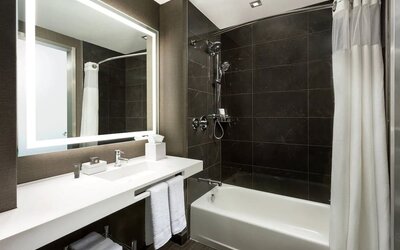 Private guest bathroom with combined shower and tub at AC Hotel New York Times Square.