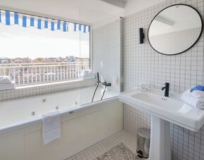 Guest bathroom with tub and natural light at Splendid Hotel & Spa Nice.
