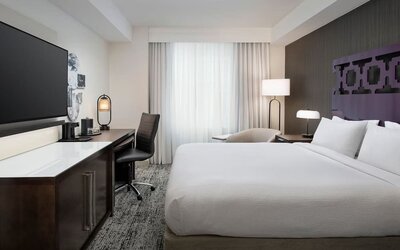Delux king room with TV, work desk, and natural light at Courtyard San Diego Downtown.