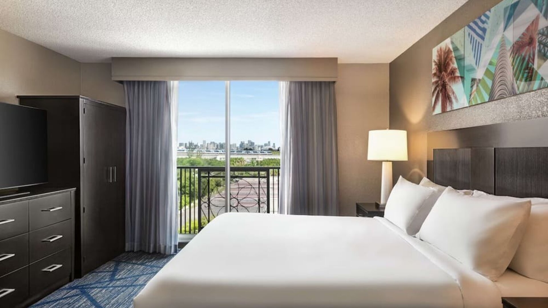 Day use room with king bed, balcony, TV screen and private bathroom at Embassy Suites By Hilton Miami - International Airport.