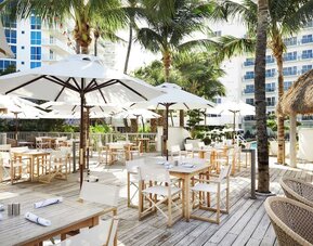 Outdoor lounge and dining area with comfortable seating at Cadillac Hotel & Beach Club, Autograph Collection.