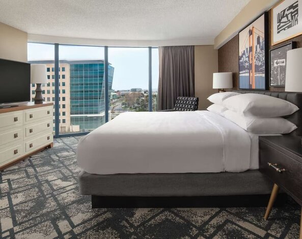 King size bed, TV and large window at Embassy Suites by Hilton San Francisco Airport.