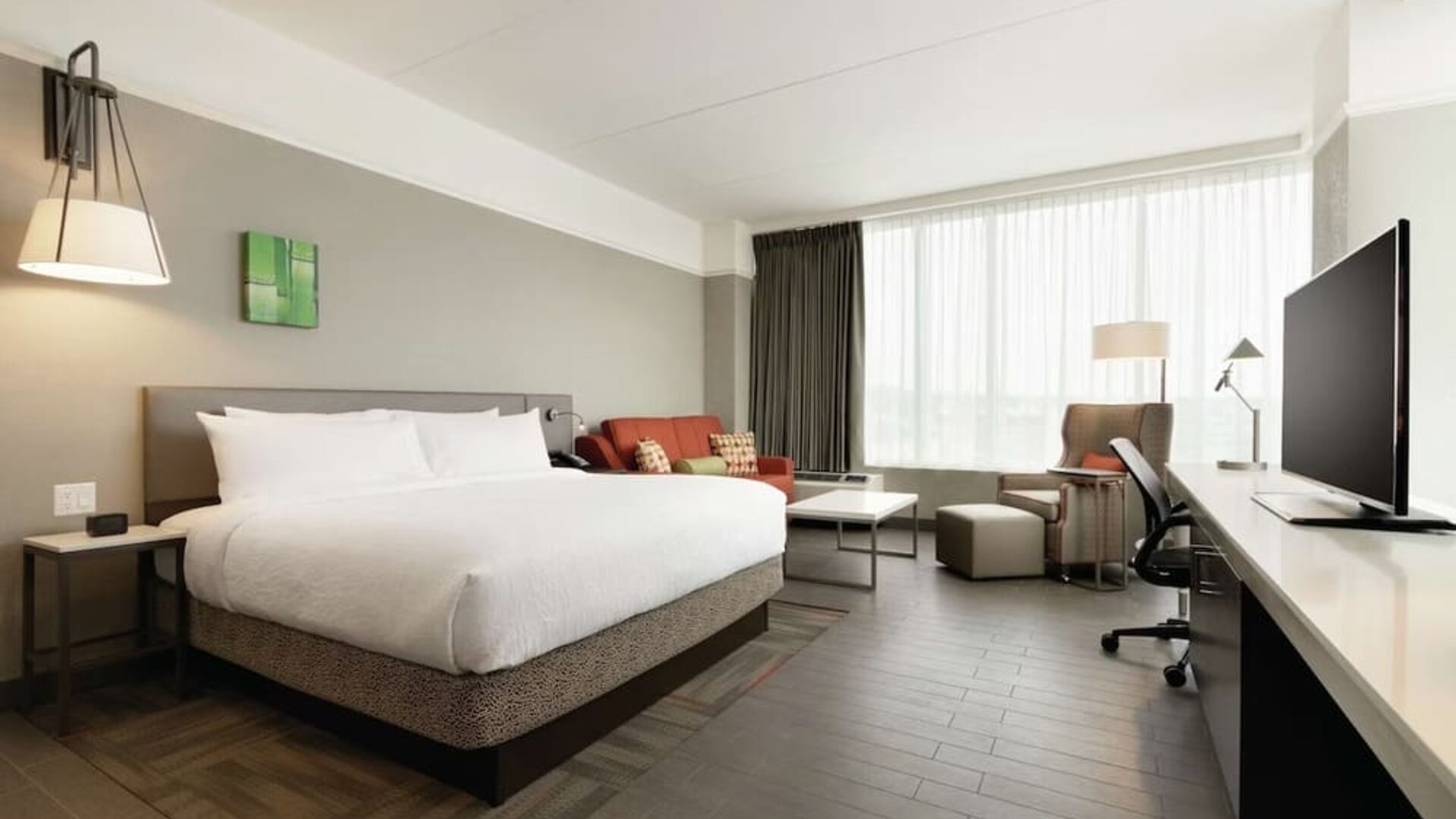 Delux king room with sofa, work desk and TV at Hilton Garden Inn Calgary Downtown.