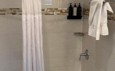 Bathroom at Madison LES Hotel with bathtub and shower with privacy curtains and towels.