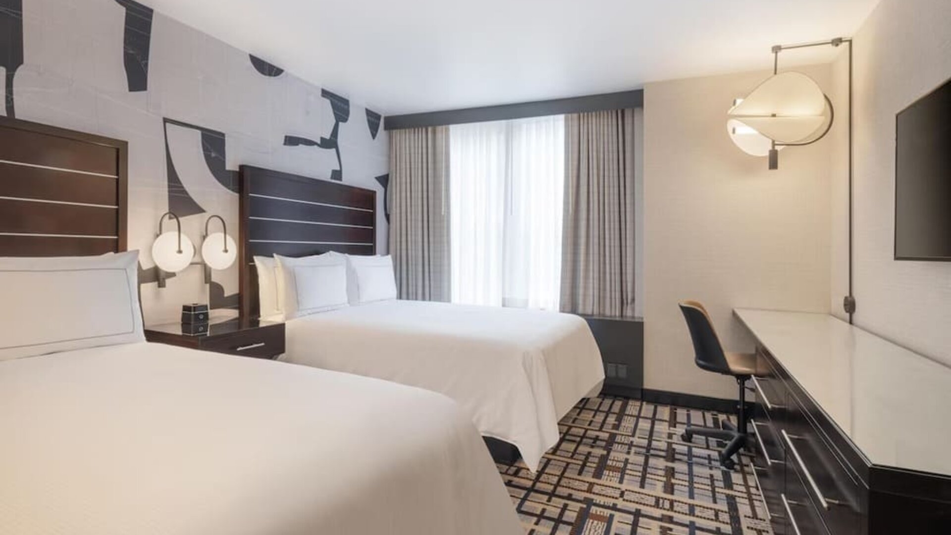 Guest room at the Hilton Fashion District, with a desk, chair and a view of the city.