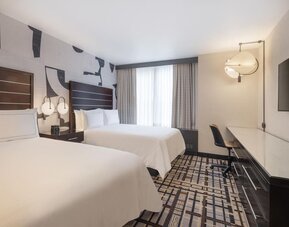 Guest room at the Hilton Fashion District, with a desk, chair and a view of the city.