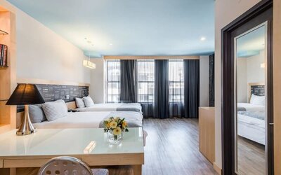 Room at the TRYP By Wyndham Times Square South containing desk, beds, and large windows.