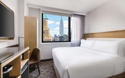 Guest room in the DoubleTree Times Square South, with a bed, beautiful view of the city and workspace desk and chair.