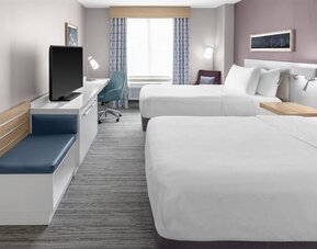 Spacious guest room at Hilton Garden Inn Queens/JFK Airport with two beds, desk, seating, and window.