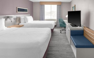 Guest room at Hilton Garden Inn Queens/JFK Airport with two double beds, desk, seating, and window.