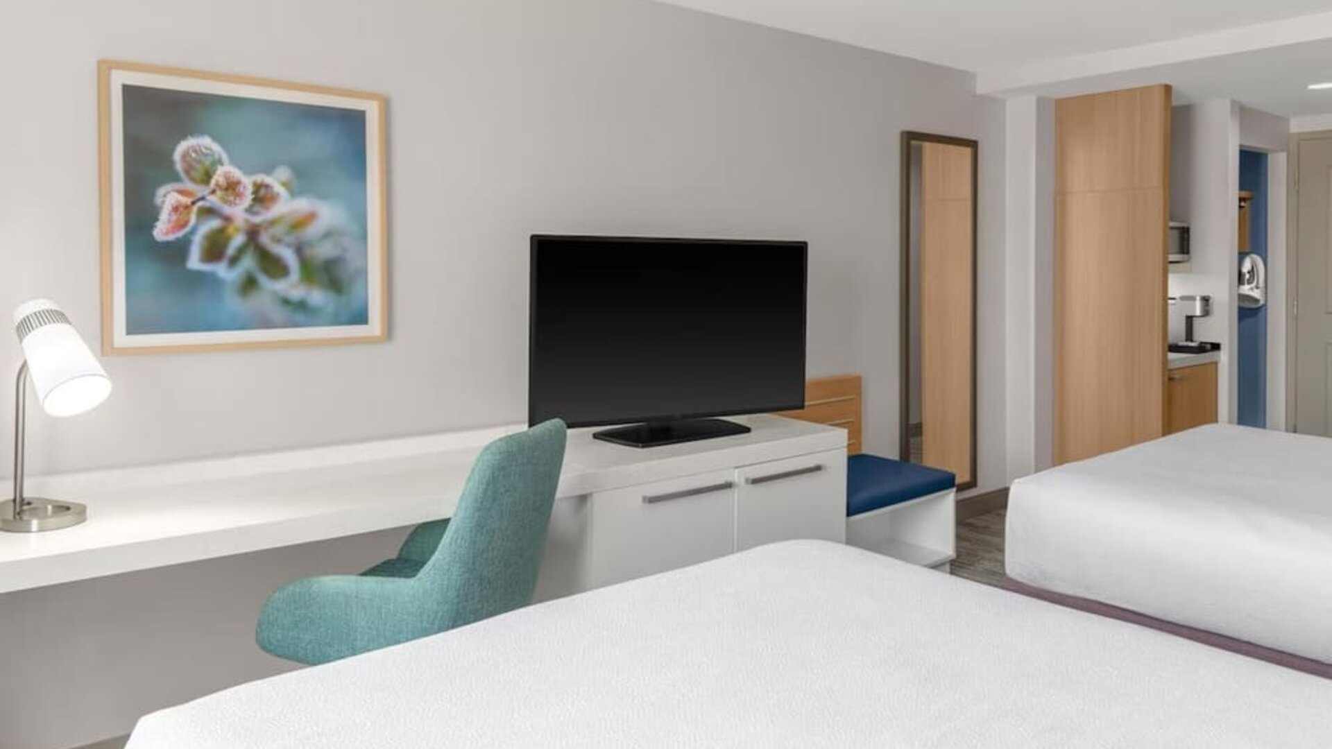 Workspace area at Hilton Garden Inn Queens/JFK Airport with desk, chair, TV and wall art.