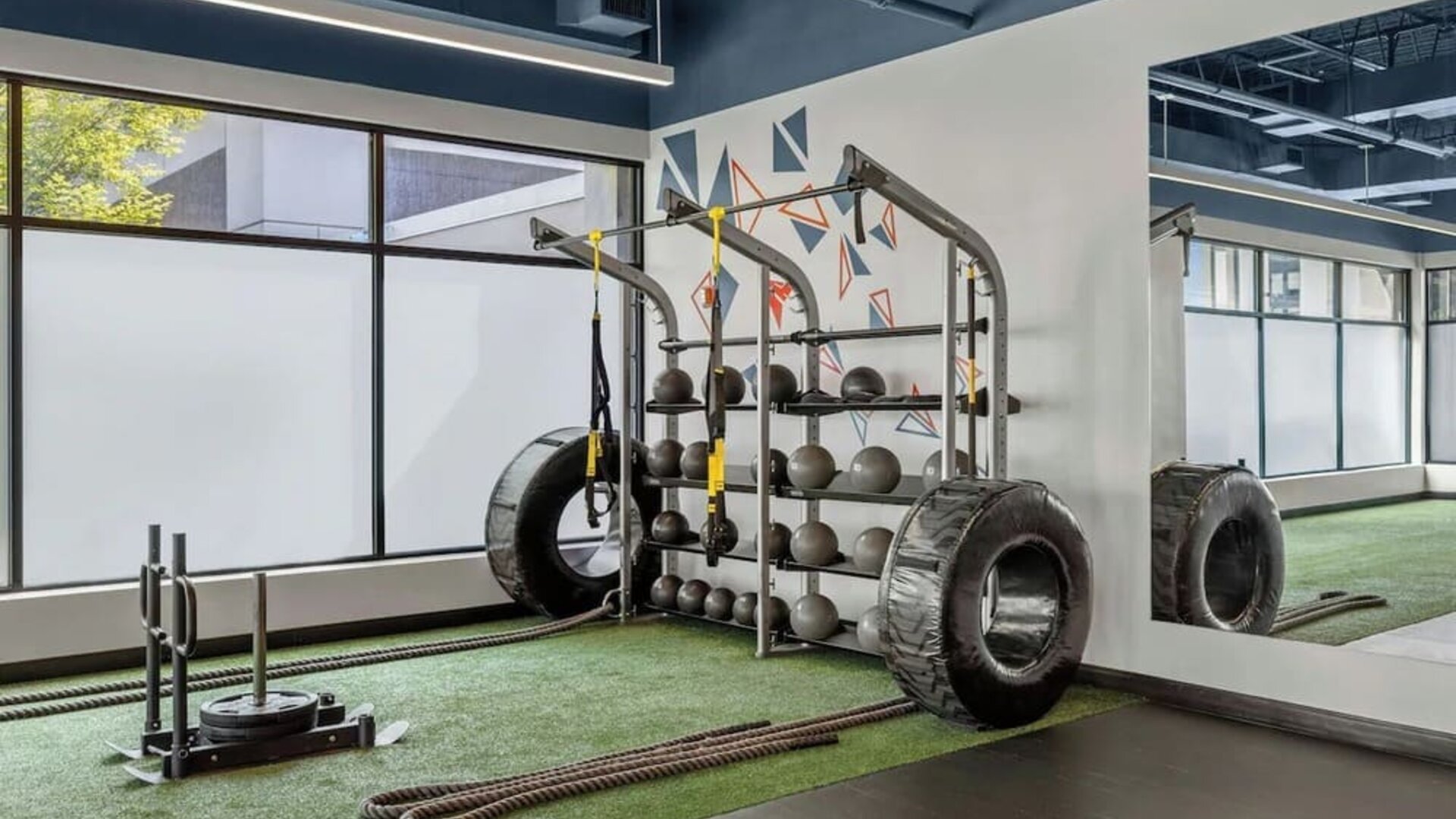 Fitness area with strength equipment, battle ropes, large tires, and mirrored wall at Renaissance Newark Airport Hotel.