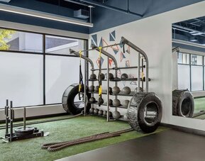 Fitness area with strength equipment, battle ropes, large tires, and mirrored wall at Renaissance Newark Airport Hotel.