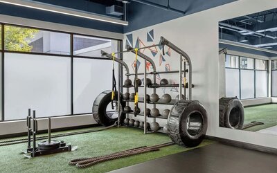 Fitness area with strength equipment, battle ropes, large tires, and mirrored wall at Renaissance Newark Airport Hotel.