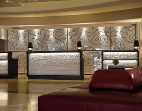 Lobby reception desks with decorative wall panels, warm lighting, and seating at Renaissance Newark Airport Hotel.