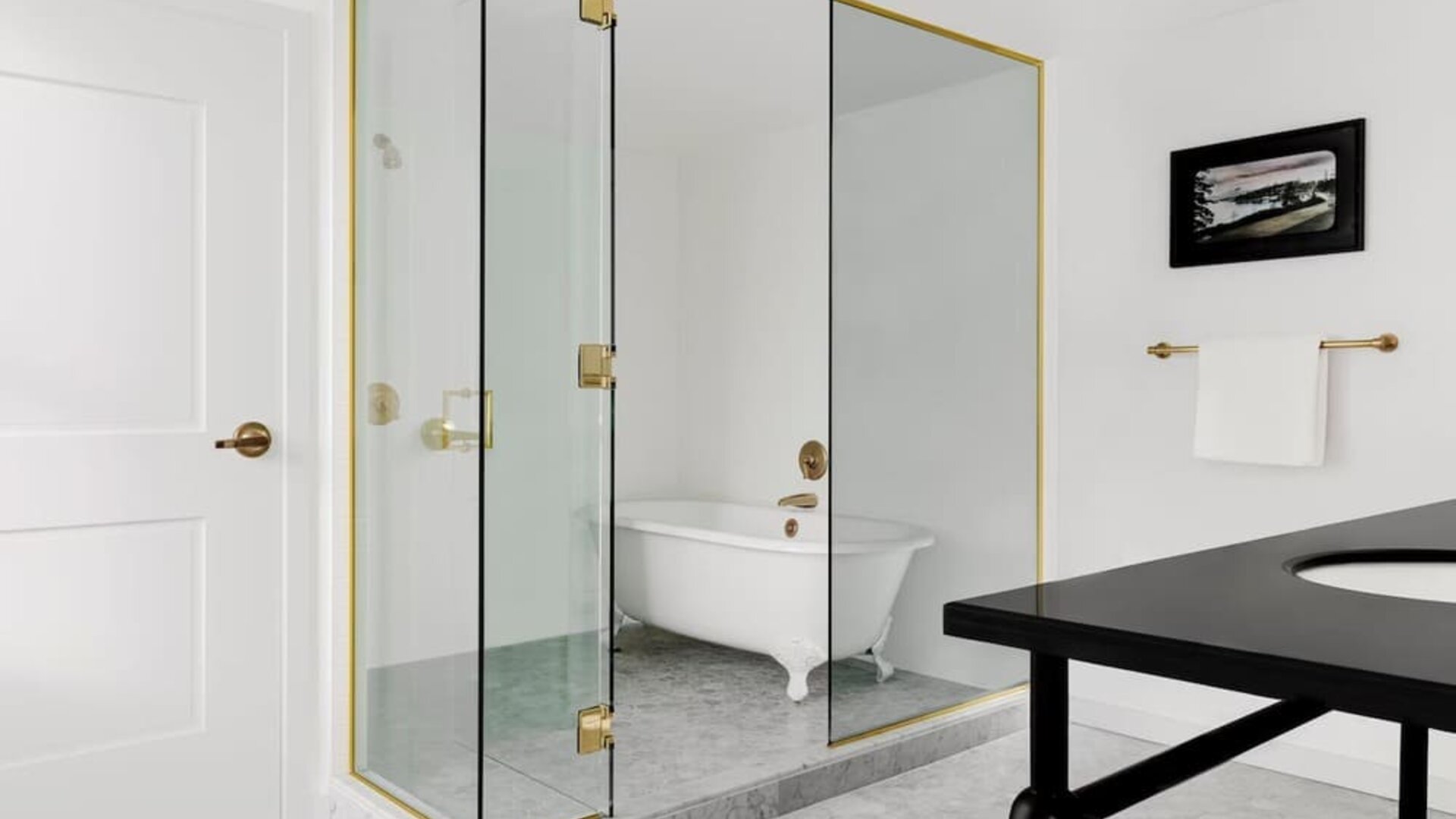 Bathroom with glass shower, freestanding clawfoot tub, white tile walls, and brass fixtures at Kimpton Palladian Hotel.