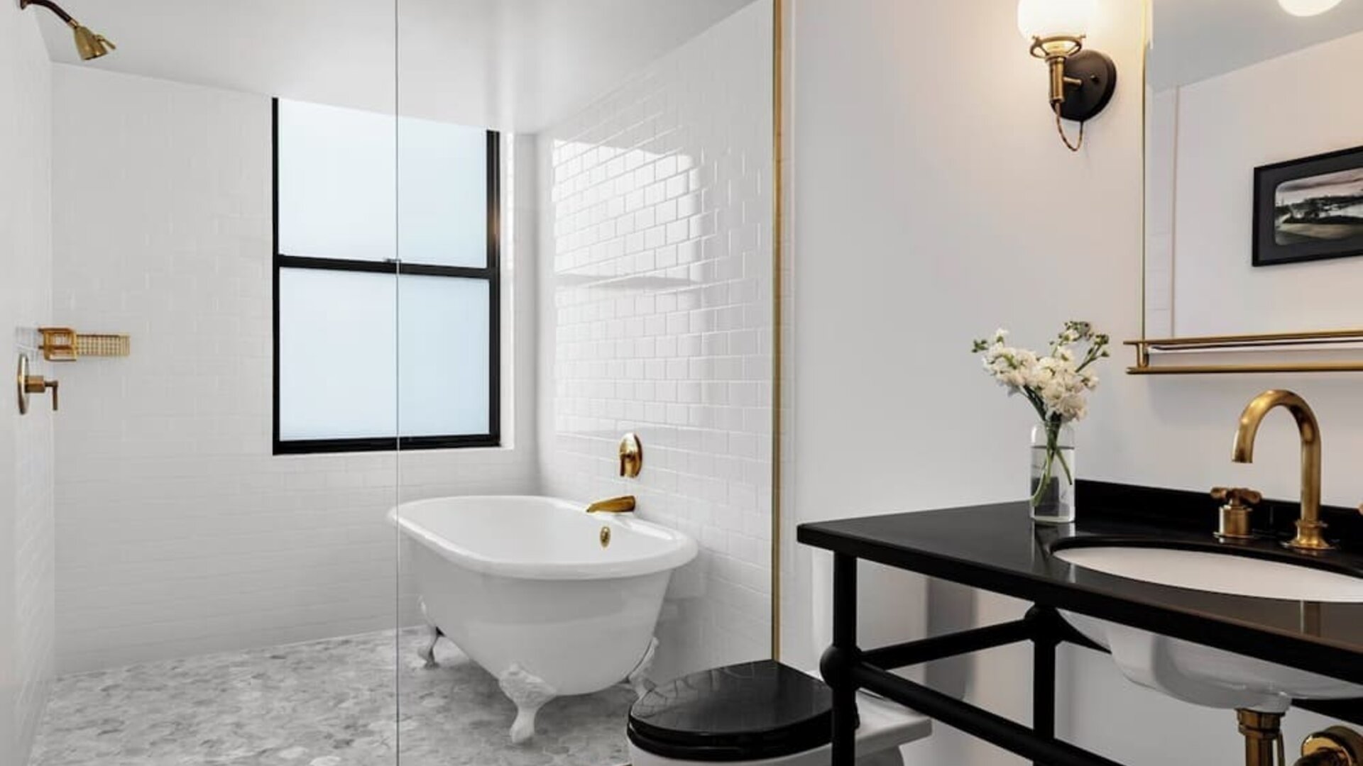Bathroom with freestanding tub, glass partition, black vanity, and gold fixtures at Kimpton Palladian Hotel.