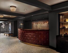 Lobby reception with curved leather desk, chandelier lighting, and seating at Kimpton Palladian Hotel.