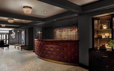 Lobby reception with curved leather desk, chandelier lighting, and seating at Kimpton Palladian Hotel.