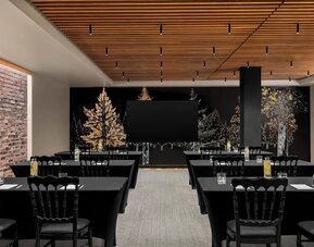 Meeting room with rows of tables, black tablecloths, chairs, and mural wall at Kimpton Palladian Hotel.