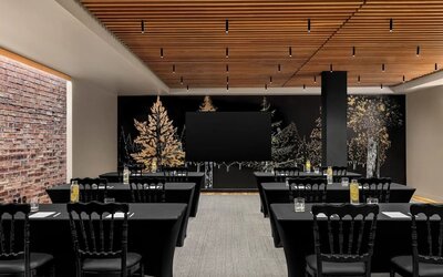 Meeting room with rows of tables, black tablecloths, chairs, and mural wall at Kimpton Palladian Hotel.