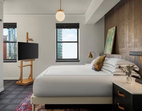 Bedroom with king bed, wood accent wall, desk, and city view window at Kimpton Palladian Hotel.