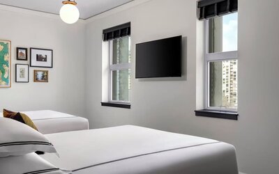 Twin bedroom with two beds, framed artwork, wall-mounted TV, and natural light at Kimpton Palladian Hotel.