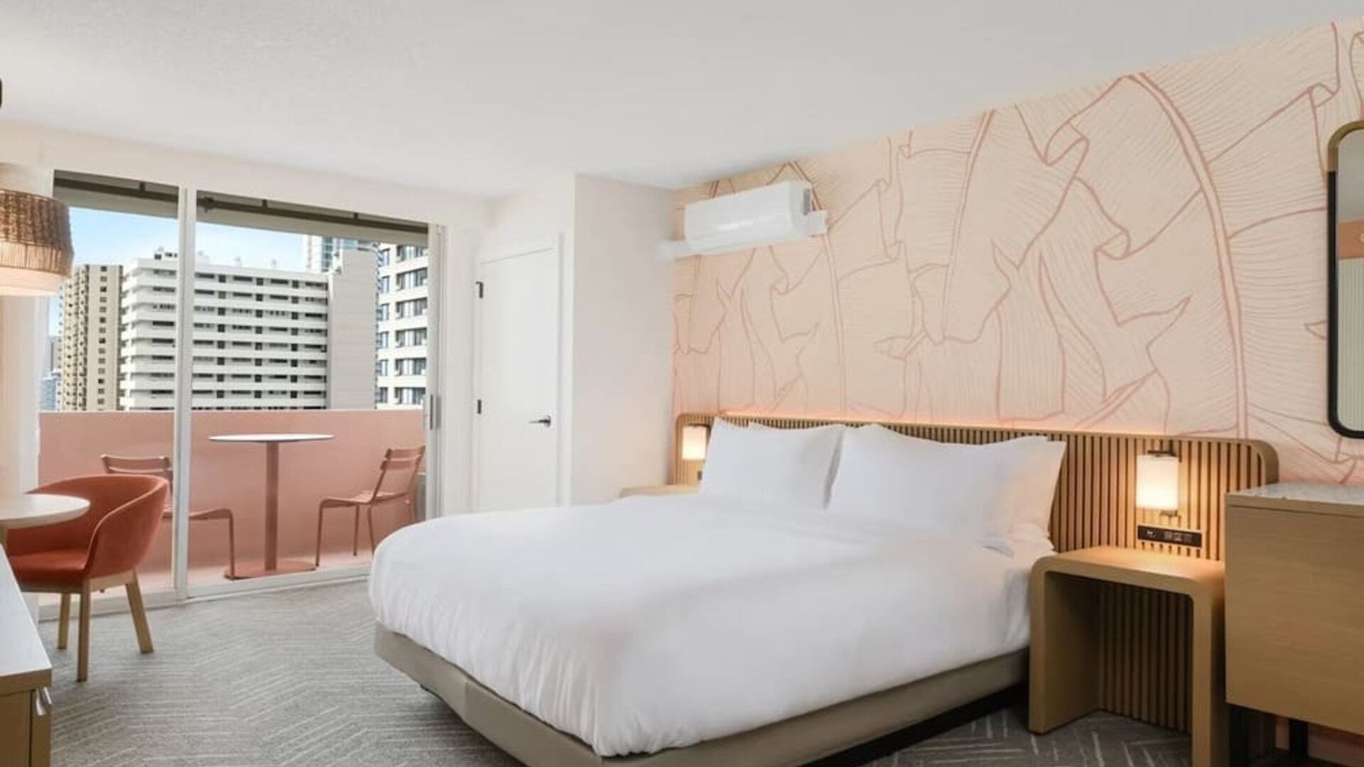 Spacious guest room with bed, seating area, and balcony access at The Ambassador Hotel Of Waikiki.