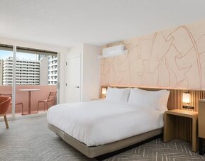 Spacious guest room with bed, seating area, and balcony access at The Ambassador Hotel Of Waikiki.