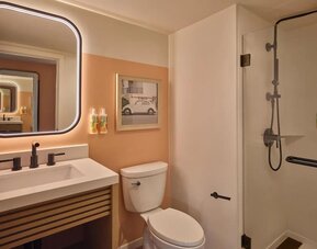 Modern bathroom with walk-in shower, illuminated mirror, and vanity at The Ambassador Hotel Of Waikiki.
