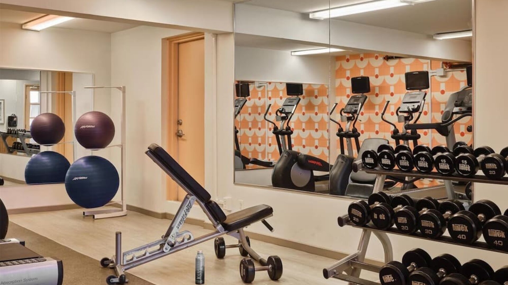 Gym area with free weights, bench, and exercise equipment at The Ambassador Hotel Of Waikiki.