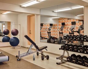 Gym area with free weights, bench, and exercise equipment at The Ambassador Hotel Of Waikiki.
