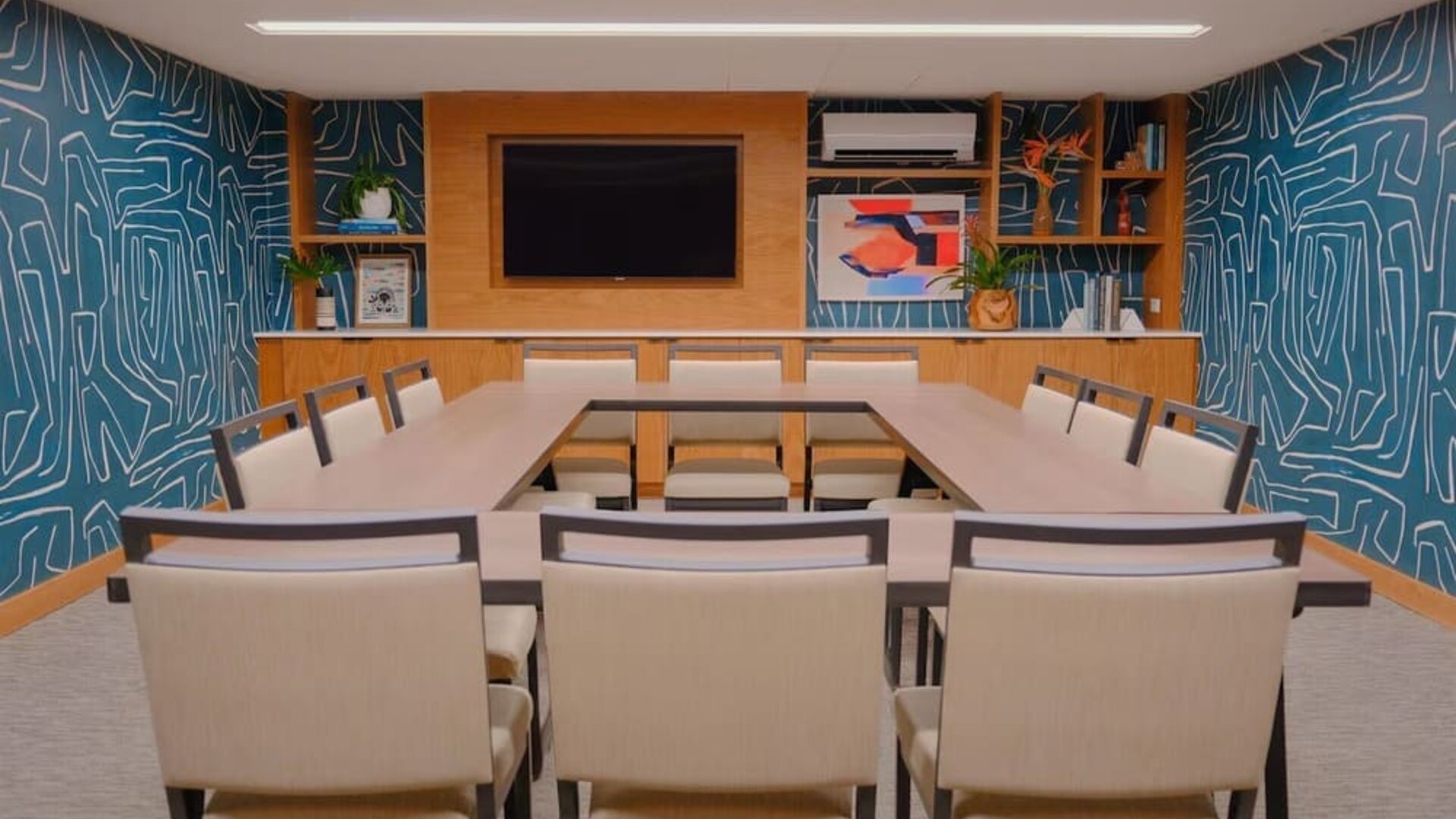 Meeting room with U-shaped table setup and presentation screen at The Ambassador Hotel Of Waikiki.