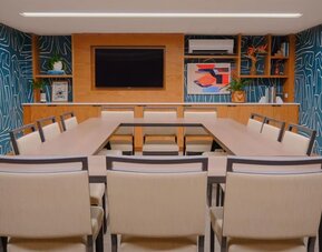 Meeting room with U-shaped table setup and presentation screen at The Ambassador Hotel Of Waikiki.