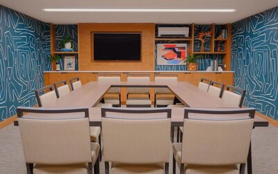 Meeting room with U-shaped table setup and presentation screen at The Ambassador Hotel Of Waikiki.