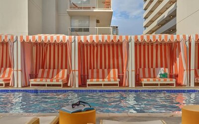 Poolside cabanas with striped fabric and lounge seating at The Ambassador Hotel Of Waikiki.