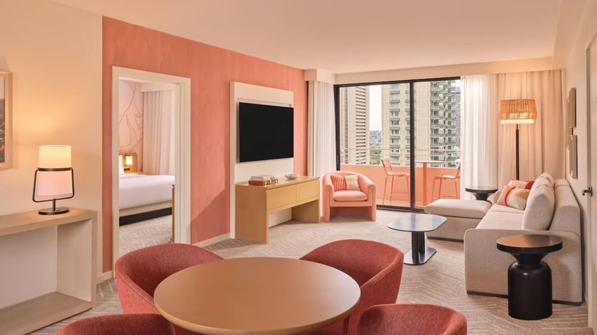 Spacious suite with dining table, lounge seating, and balcony access with city views at The Ambassador Hotel Of Waikiki.